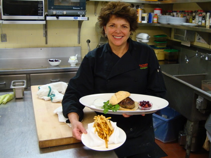 Chef Gloria holding her Moroccan Spiced Lamb Burger and Harissa Fries
